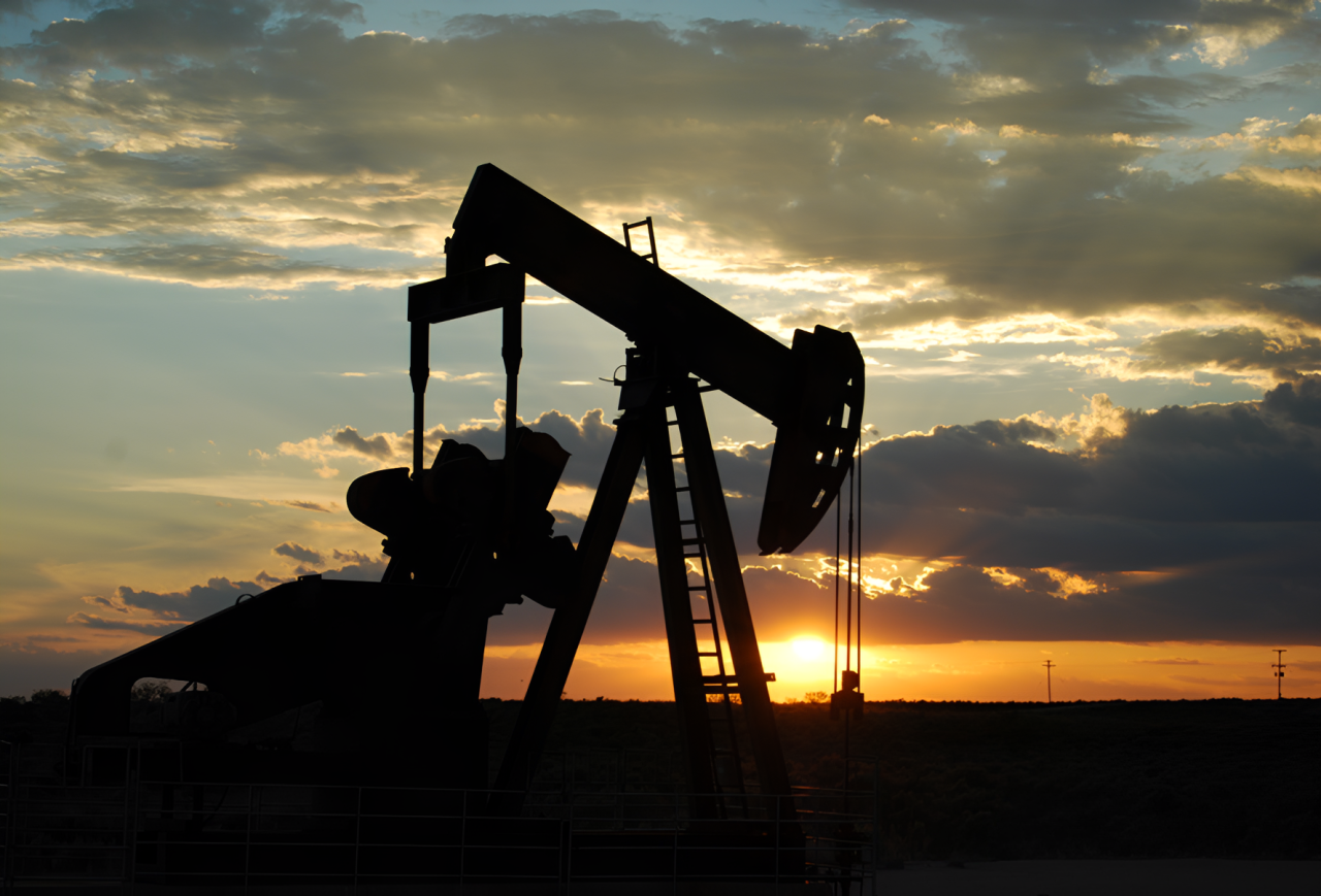 Oil pumpjack silhouetted against sunset sky